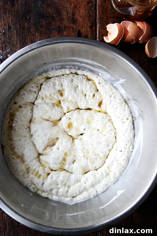Adding fresh eggs and golden honey to the active Challah dough sponge.