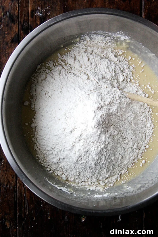 Incorporating the final portion of flour into the Challah bread dough mixture.