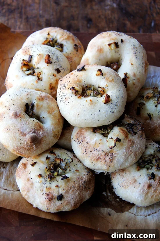 Every batch of bialys disappears quickly — the onion-poppy seed-breadcrumb filling/topping, whose flavor permeates the whole bialy, is irresistible. Later in the day we halve them and spread them with softened butter or cream cheese. For dinner we toast them under the broiler, one half covered with a slice of cheddar, and then, upon pulling them from the oven, we slide a fried egg onto the uncheesed half and hit it with a healthy squirt of Sriracha. // alexandracooks.com A pile of freshly baked bialys, golden brown with savory onion-poppy seed filling.