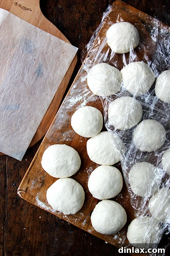 Your Guide to Perfect Homemade Bialys 10 Bialy dough balls rising gently on a wooden board, indicating they are ready for shaping.