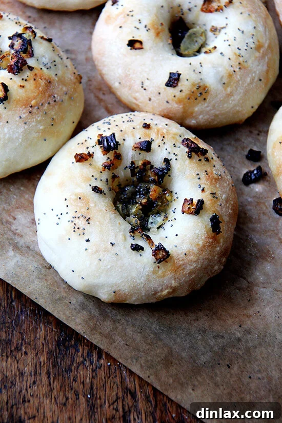 Your Guide to Perfect Homemade Bialys 15 A single, perfectly baked bialy with its signature onion and poppy seed filling, cooling on a board.