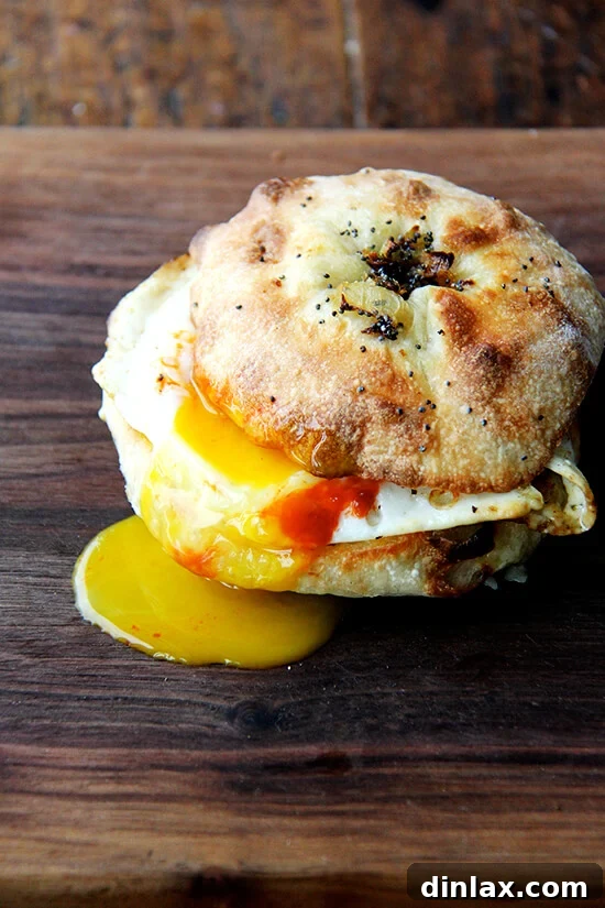 Your Guide to Perfect Homemade Bialys 17 A delicious bialy egg sandwich featuring melted cheddar, a fried egg, and a drizzle of sriracha.