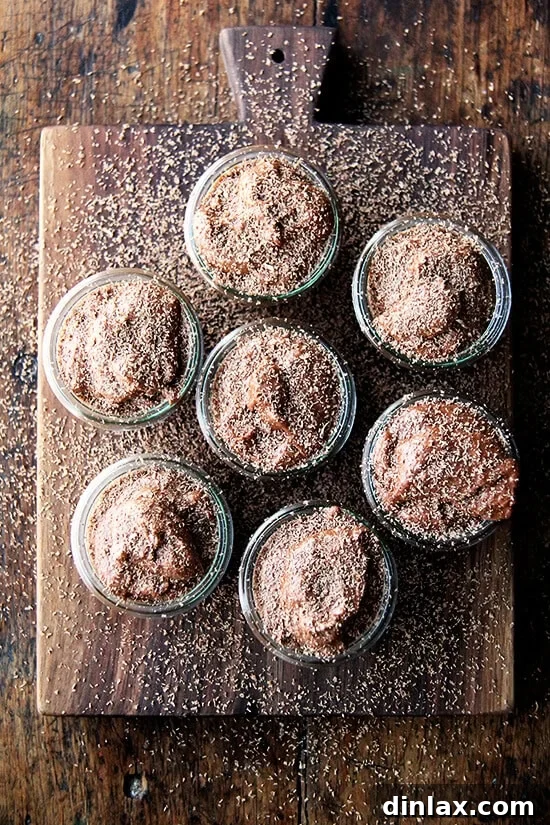 Julia Child's Chocolate Mousse: A Timeless, Make-Ahead Valentine's Day Dessert with a Unique, Lightly Chewy Texture from Beaten Egg Whites. Overhead shot of jars filled with rich chocolate mousse, elegantly topped with delicate chocolate shavings, perfect for a romantic Valentine's Day dessert.