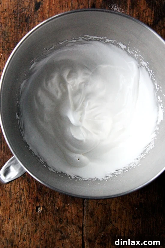 Julia Child's Signature Chocolate Mousse 3 Fluffy, peaks of beaten egg whites resting in a mixing bowl, showcasing the ideal texture before being folded into chocolate mousse.
