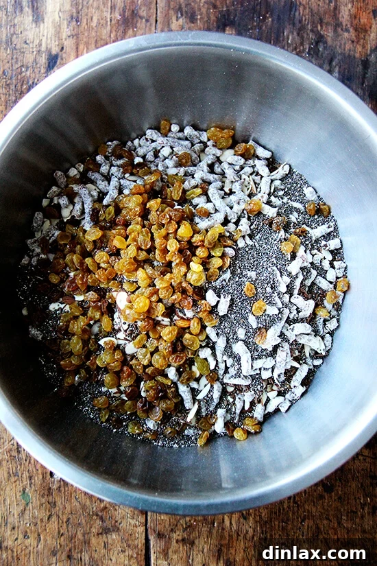 A large bowl filled with an unmixed array of dry ingredients for muesli, featuring oats, various nuts, and dried fruits, before stirring.