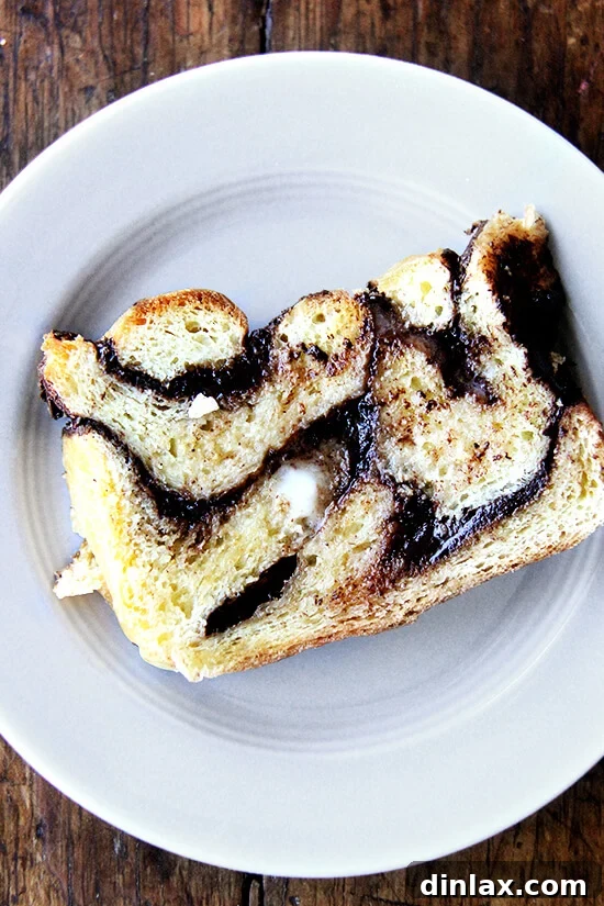 Mastering Chocolate Swirl Babka 13 A slice of day-old babka, perfectly toasted and generously spread with butter, resting on a plate.