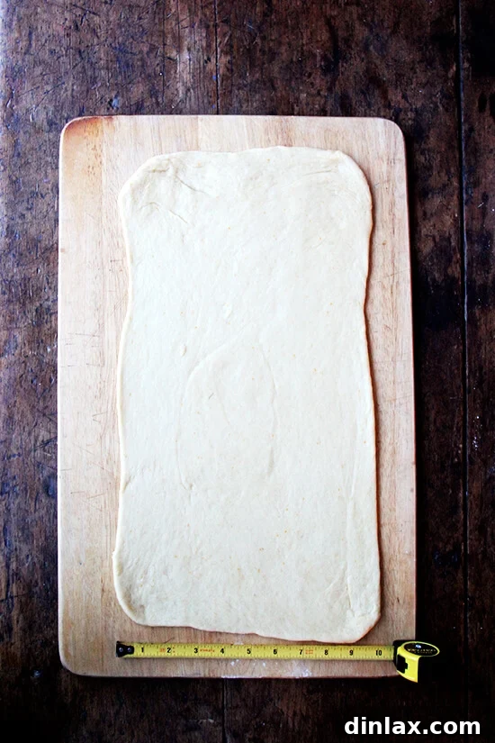 Mastering Chocolate Swirl Babka 4 A portion of babka dough being expertly rolled out into a thin, even rectangle on a lightly floured surface.