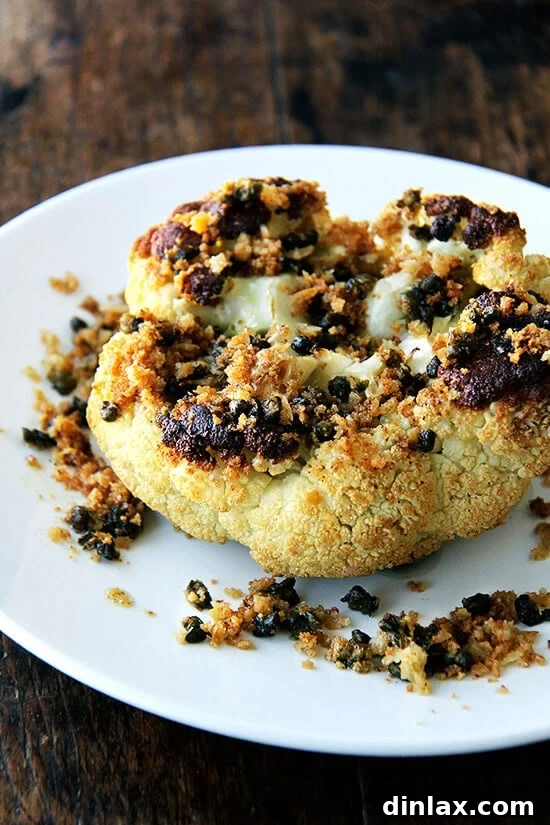 Golden brown whole roasted cauliflower with crispy fried capers and nutty brown butter breadcrumbs, served on a platter. A perfect vegetarian centerpiece.