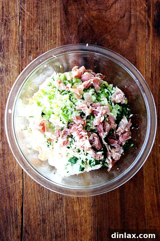 The savory calzone filling, a perfect blend of cheeses, minced garlic, fresh herbs, and diced prosciutto, ready to be spread onto dough rounds.