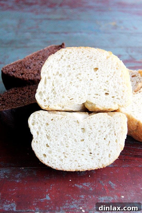 A freshly baked peasant bread loaf, expertly halved to reveal its soft, airy interior crumb and inviting texture.