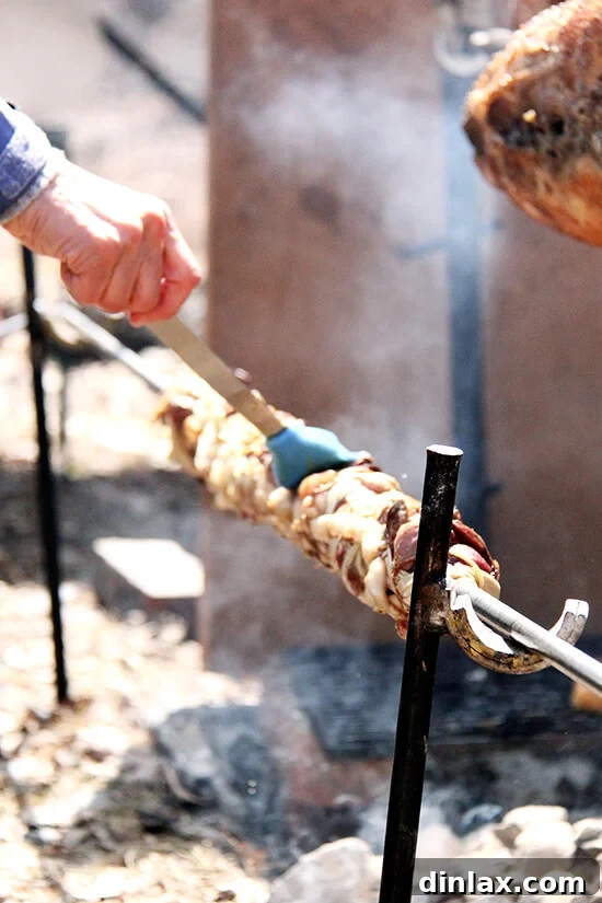 Carefully basting the kokoretsi as it slowly roasts to a perfect golden brown, ensuring maximum flavor.