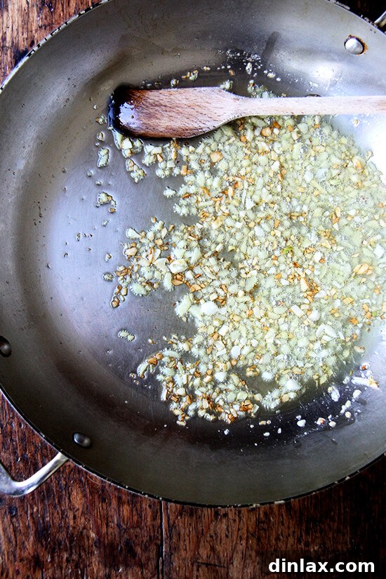 Ginger and garlic sizzling in a skillet with hot oil, beginning to brown and crisp up.