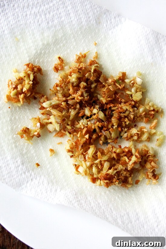 Golden-brown, crispy fried ginger and garlic, drained on paper towels, ready to be sprinkled as a garnish.