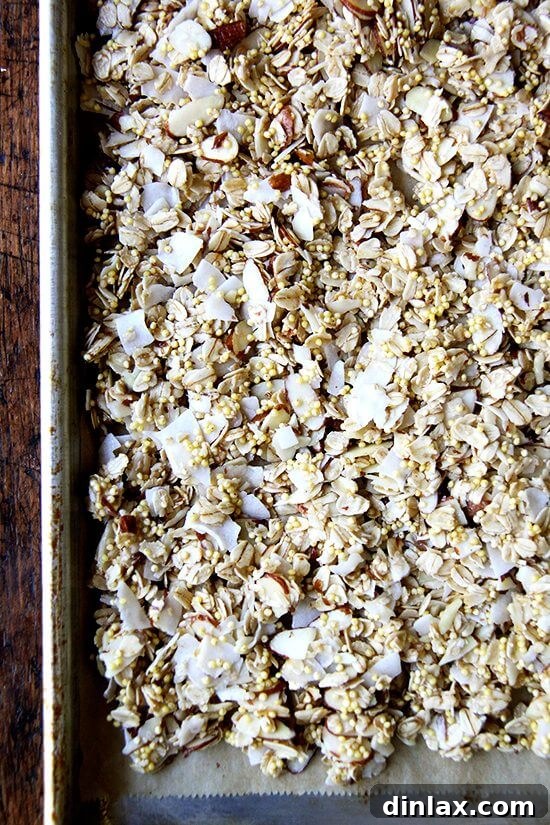 Raw granola mix spread on a baking sheet, ready for pre-baking.