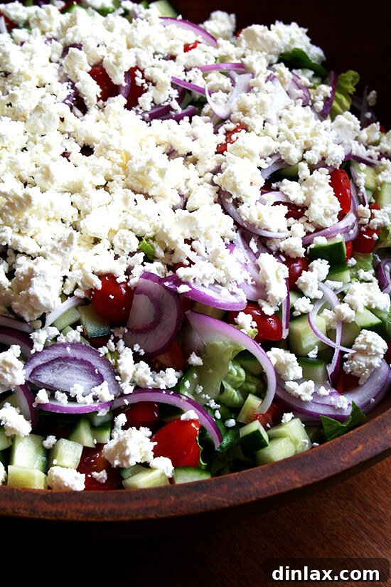 A large, colorful Greek salad with fresh vegetables, feta cheese, and olives, dressed in a classic vinaigrette.