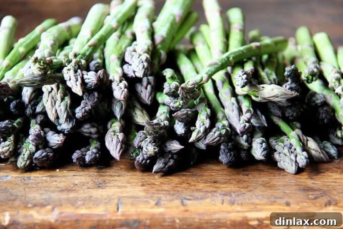 Canal House Spring Shaved Asparagus and Arugula Salad 4 Fresh green asparagus spears laid out on a clean wooden cutting board.