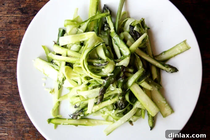 Canal House Spring Shaved Asparagus and Arugula Salad 9 Shaved asparagus ribbons coated in creamy dressing in a white bowl.
