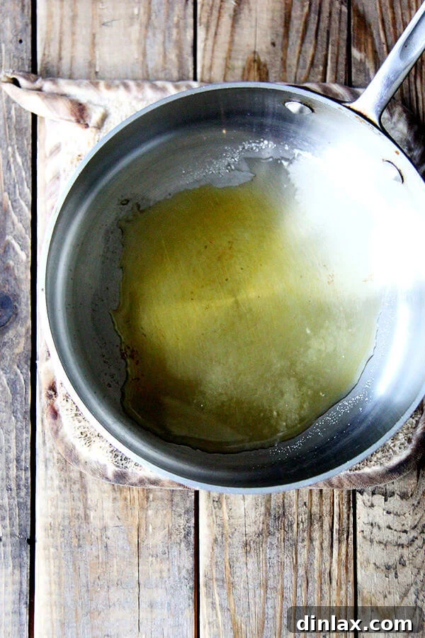 Caramelizing sugar in a saucepan, showing the golden-brown stage before adding nuts.