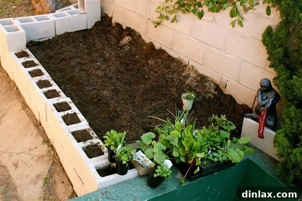Close-up of a cinder block garden under construction, showing the weed barrier and initial soil mix.