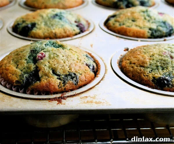 Close-up of baked tri-berry muffins, showcasing their golden-brown tops and juicy berry filling. Ideal for a quick snack or dessert.