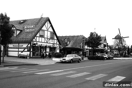 A beautiful street scene in Solvang, California, featuring iconic Danish architecture, well-maintained buildings, and a clear, sunny sky, inviting leisurely exploration.