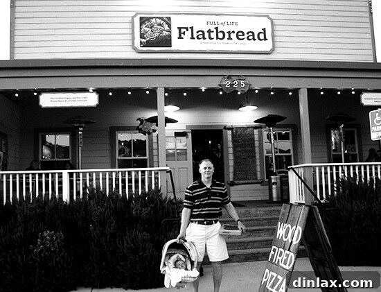 A close-up of a delectable wood-fired flatbread from Full of Life Flatbread in Los Alamos, showcasing its artisanal crispy crust and fresh, vibrant toppings.