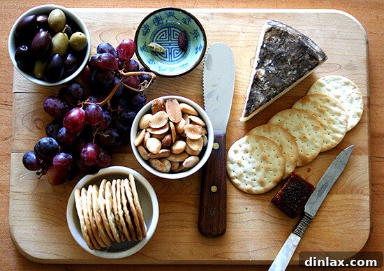 An appetizing cheese plate featuring creamy Tomme de Savoie, sweet red grapes, and crunchy Marcona almonds, part of a gourmet picnic spread.