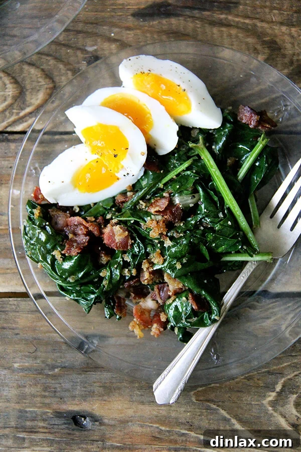 This warm spinach salad calls for gently wilting the spinach in a stainless steel bowl set over simmering water. Cool, right? And bacon and breadcrumbs make everything better. Am I right? // alexandracooks.com A plate of warm spinach salad with crispy bacon and golden bread crumbs, ready to be enjoyed.