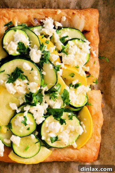 A vibrant Summer Squash Tart with Ricotta and Feta, boasting golden edges and a medley of fresh ingredients, captured beautifully for a recipe feature. Perfect for summer gatherings.