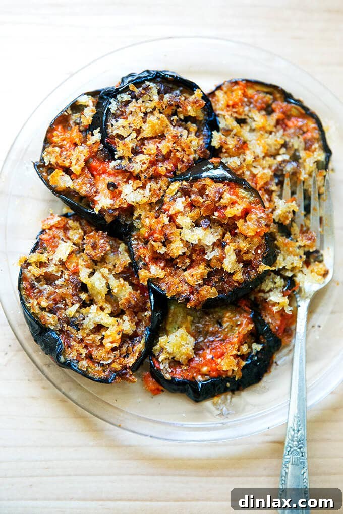 A generous serving of baked eggplant parmesan on a white plate, garnished with fresh basil.
