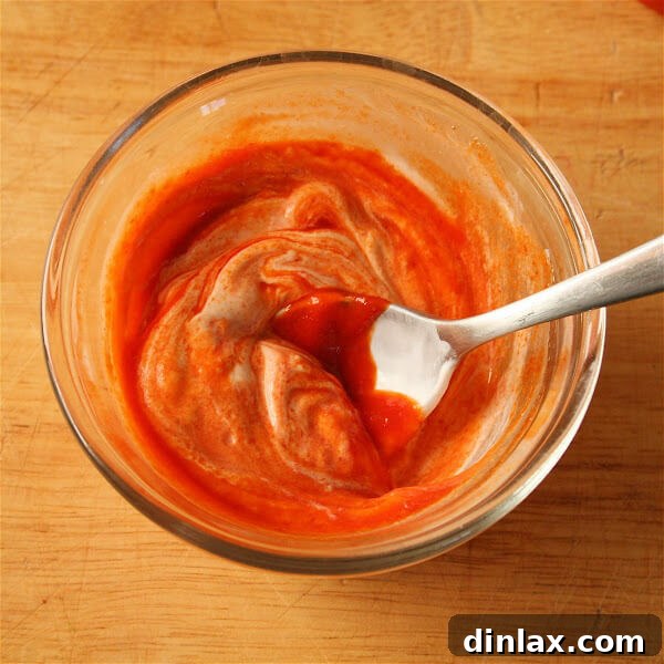 Close-up of a perfectly assembled fish taco, showcasing flaky halibut, creamy sriracha-sour cream, and vibrant mango-jicama slaw, ready to be enjoyed.