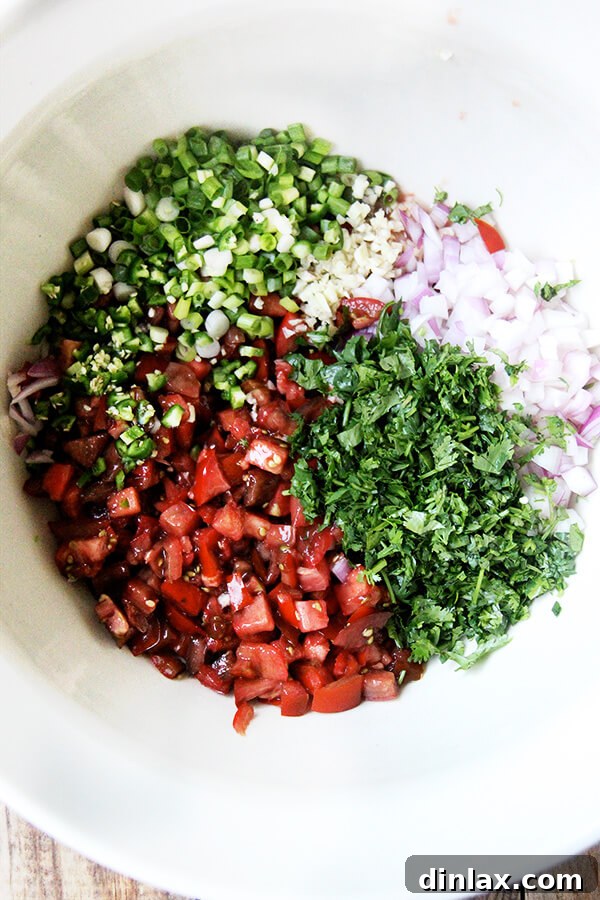 A large mixing bowl filled with freshly chopped tomatoes, onions, and other salsa ingredients, ready to be combined.