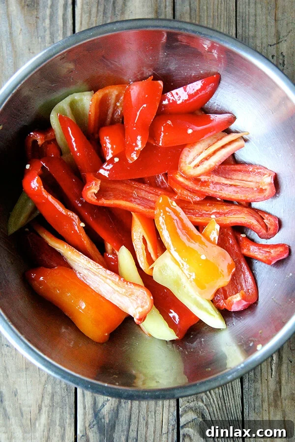 Precision in simplicity: Close-up of bell peppers neatly cut into strips, highlighting the straightforward preparation required before they hit the oven for their magical transformation. Bell peppers freshly cut into strips, showcasing their internal structure and readiness for seasoning and roasting. This simple preparation step is key to the 'magic' of the recipe.