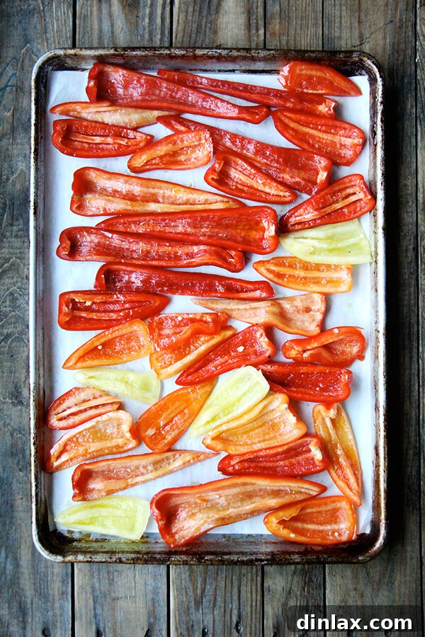 Oven-bound beauty: A baking sheet filled with perfectly seasoned pepper strips, awaiting their quick roast to caramelize and soften into tender, flavorful "Magic Peppers." Pepper strips seasoned with olive oil, salt, and pepper, spread evenly on a baking sheet, ready for high-heat roasting in the oven to achieve caramelized perfection.