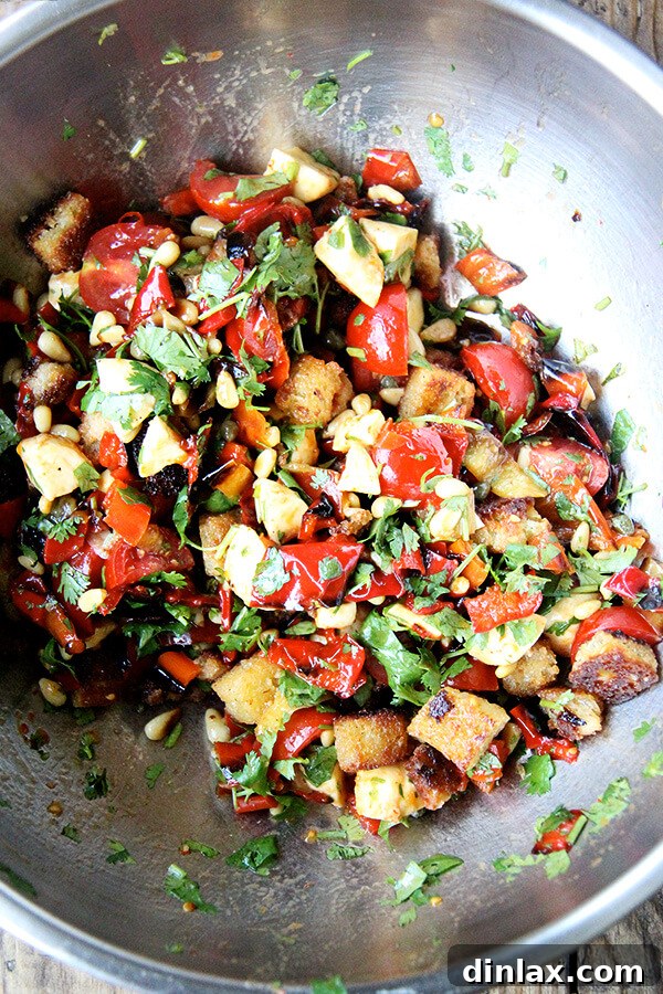 A symphony of flavors: The colorful medley of "Magic Peppers" and fresh salad ingredients, expertly tossed together, creating a visually appealing and highly appetizing mixture. All the vibrant salad ingredients—'Magic Peppers,' tomatoes, mozzarella, capers, pine nuts, and herbs—tossed together in a bowl, dressed and ready for the addition of bread.