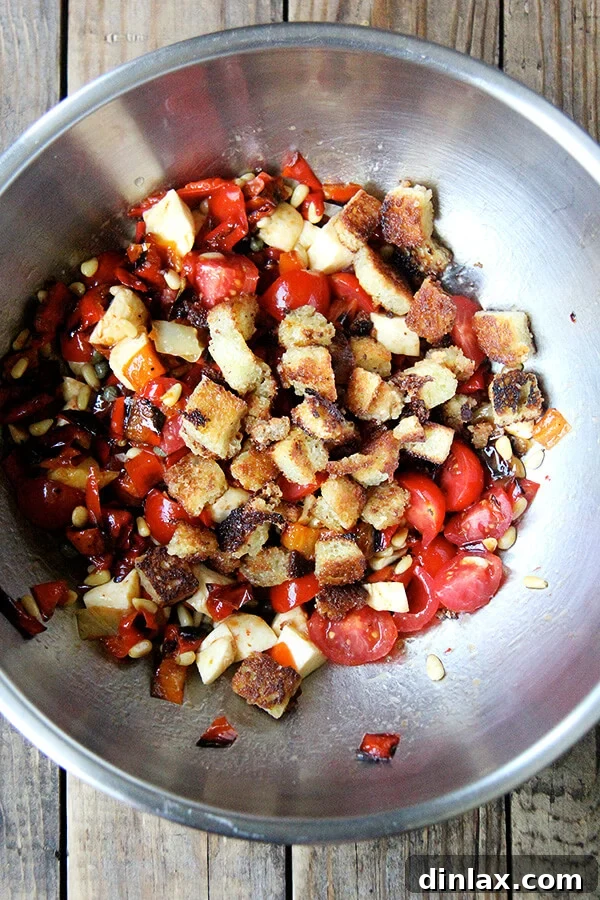 The crucial addition: Hand-tossing crispy, olive oil-fried bread cubes into the "Magic Peppers" salad, illustrating the final step in crafting a perfect panzanella. Golden, olive oil-fried bread cubes being added to the tossed 'Magic Peppers' salad, completing the panzanella and adding a satisfying textural element.