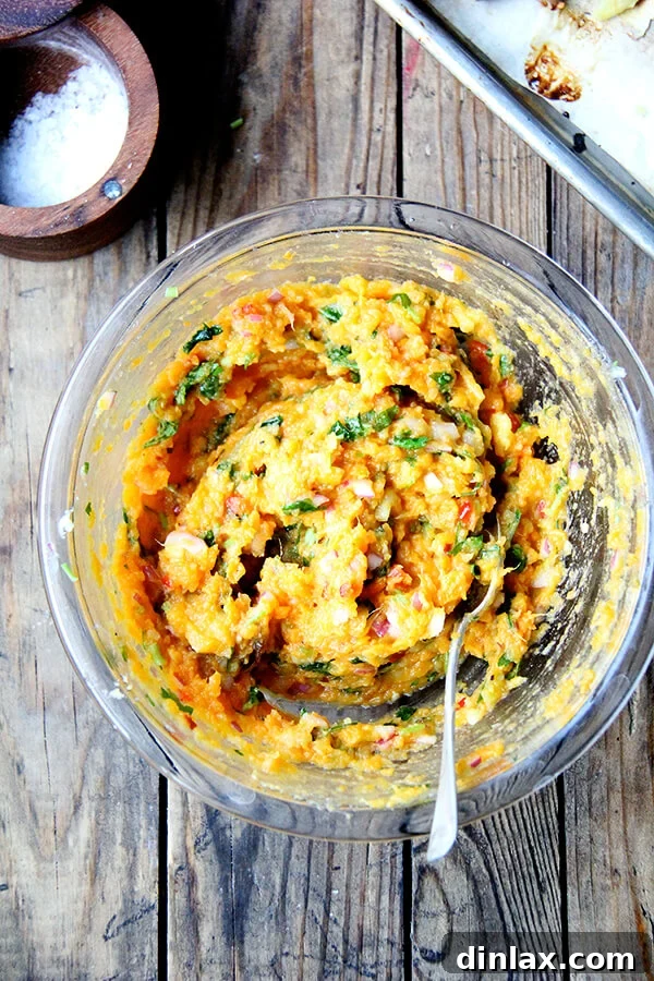 A beautifully presented bowl of creamy mashed sweet potatoes, generously mixed with zesty lime, spicy chilies, and fresh cilantro, and garnished with additional herbs. This vibrant and flavorful side dish is ready to be served, offering a refreshing culinary experience.