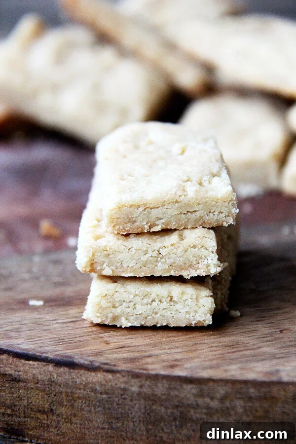 A close-up of a stack of brown sugar shortbread cookies, showcasing their golden color and crumbly texture. This easy recipe uses only three ingredients for a perfect sweet and salty treat.
