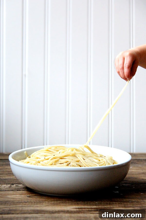 A forkful of creamy Cacio e Pepe, ready to be enjoyed. Cacio e pepe, a classic Italian dish, relies on starchy pasta cooking water to form a creamy emulsion with butter and cheese, often Parmigiano Reggiano and Pecorino Romano, and it couldn't be more delicious or simple. I like simple. // alexandracooks.com
