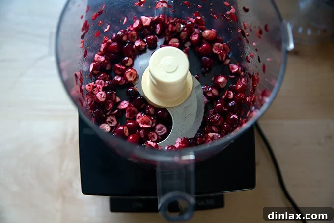 Pulsed fresh cranberries in a food processor, showing their coarsely chopped texture, ideal for scone dough.
