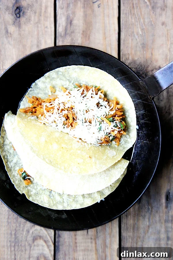 Two sweet potato quesadillas cooking in a hot pan, showing a golden-brown exterior as the cheese melts within.