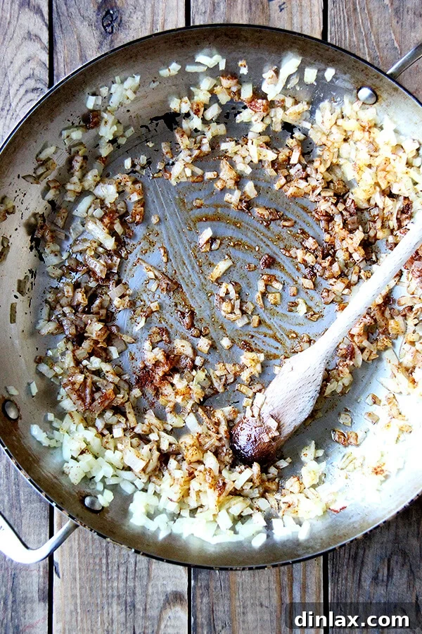 Finely chopped onions sautéing in a large pan over medium heat, becoming translucent and fragrant.