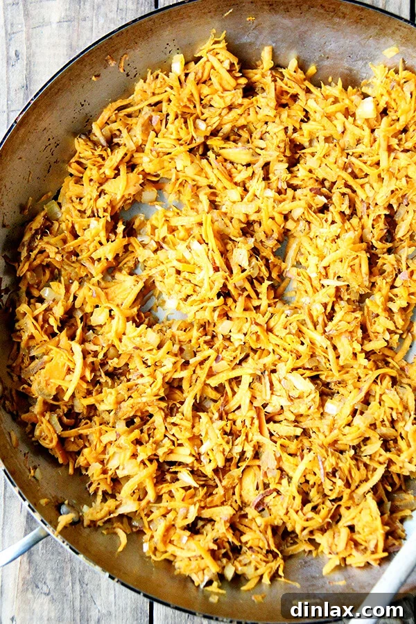 The fully cooked sweet potato filling, a mixture of tender grated sweet potatoes, onions, and spices, resting in a sauté pan.