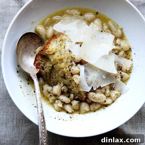 A close-up of a rustic bowl of Marcella Hazan's White Beans with Garlic and Sage, showcasing their rich, creamy texture and vibrant green sage leaves.