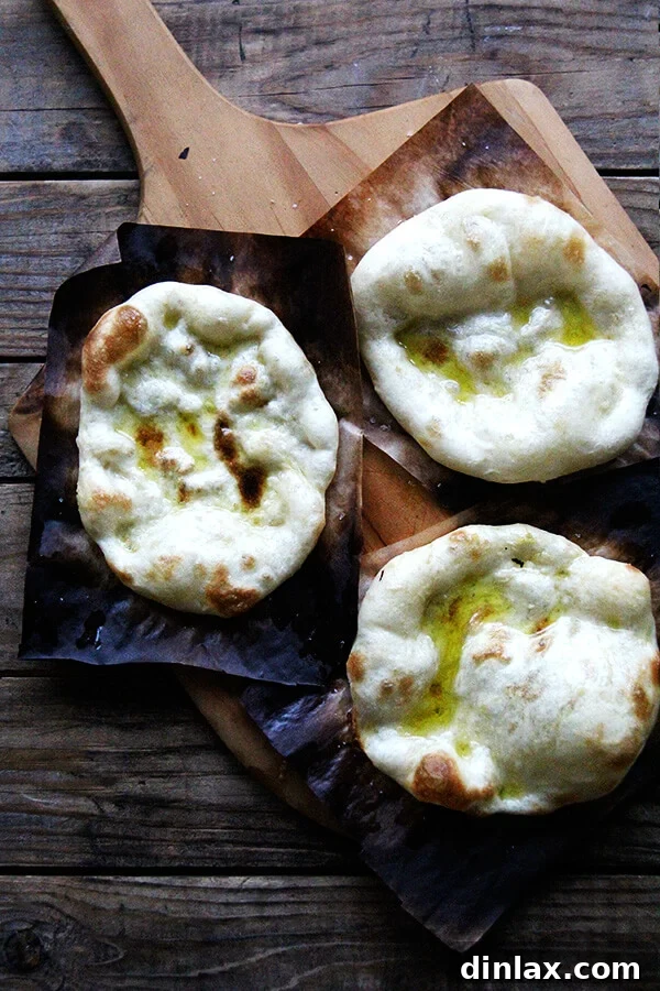 A stack of perfectly baked flatbreads fresh out of the oven, exhibiting a slightly charred and puffed texture. These versatile breads are an ideal accompaniment for the two-lentil dal, perfect for scooping up its rich flavors.