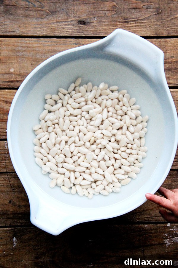 A bowl of dried white beans soaking in water, a crucial first step for perfectly cooked beans.
