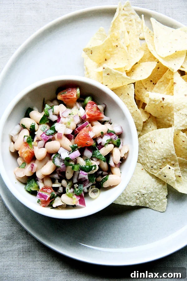 A delicious bowl of white bean and orange salsa served alongside crispy tortilla chips, ready for dipping.