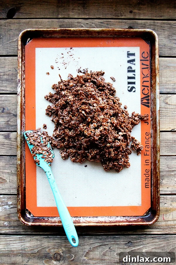 Spreading the cocoa crunch mixture evenly onto a Silpat-lined baking sheet.