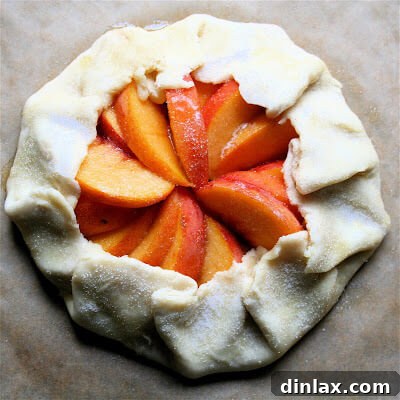 A close-up shot of an unbaked peach galette, showing the neatly arranged peach slices and the folded-over dough border, ready for the oven.