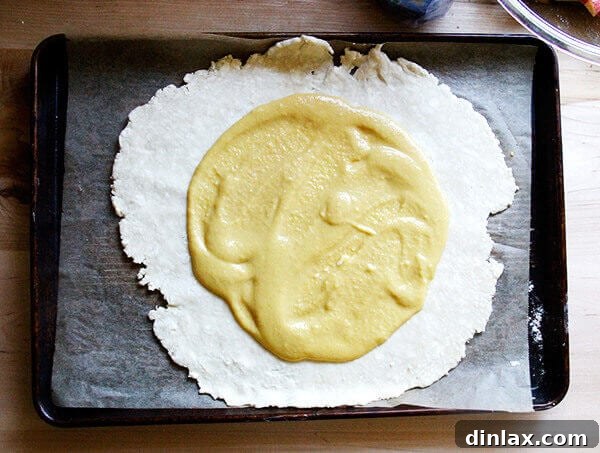 A bowl of creamy, light brown frangipane filling with a spoon, ready to be used in a tart.